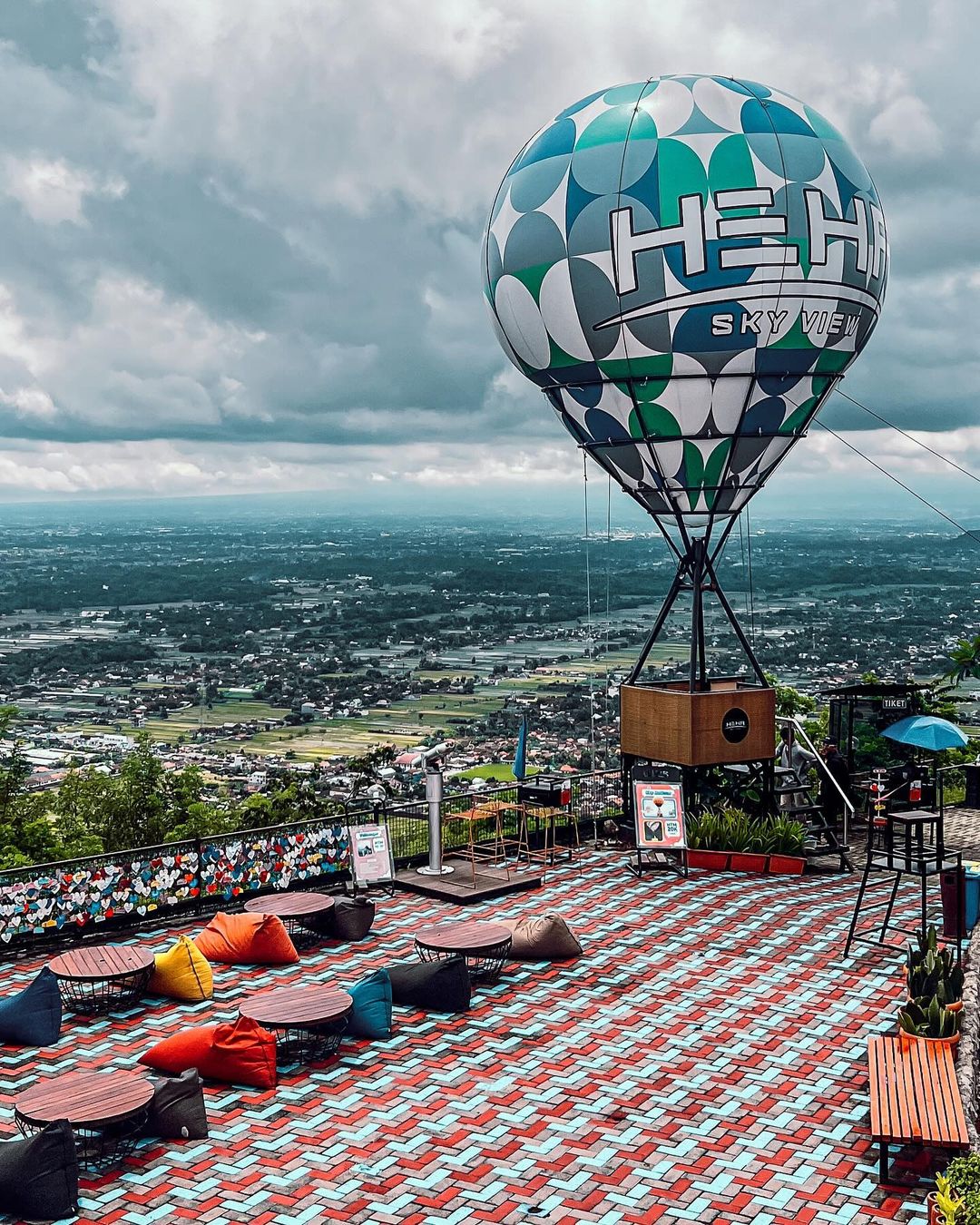 HeHa Sky View's hot air balloon attraction with colorful bean bags and tables on a patterned terrace.