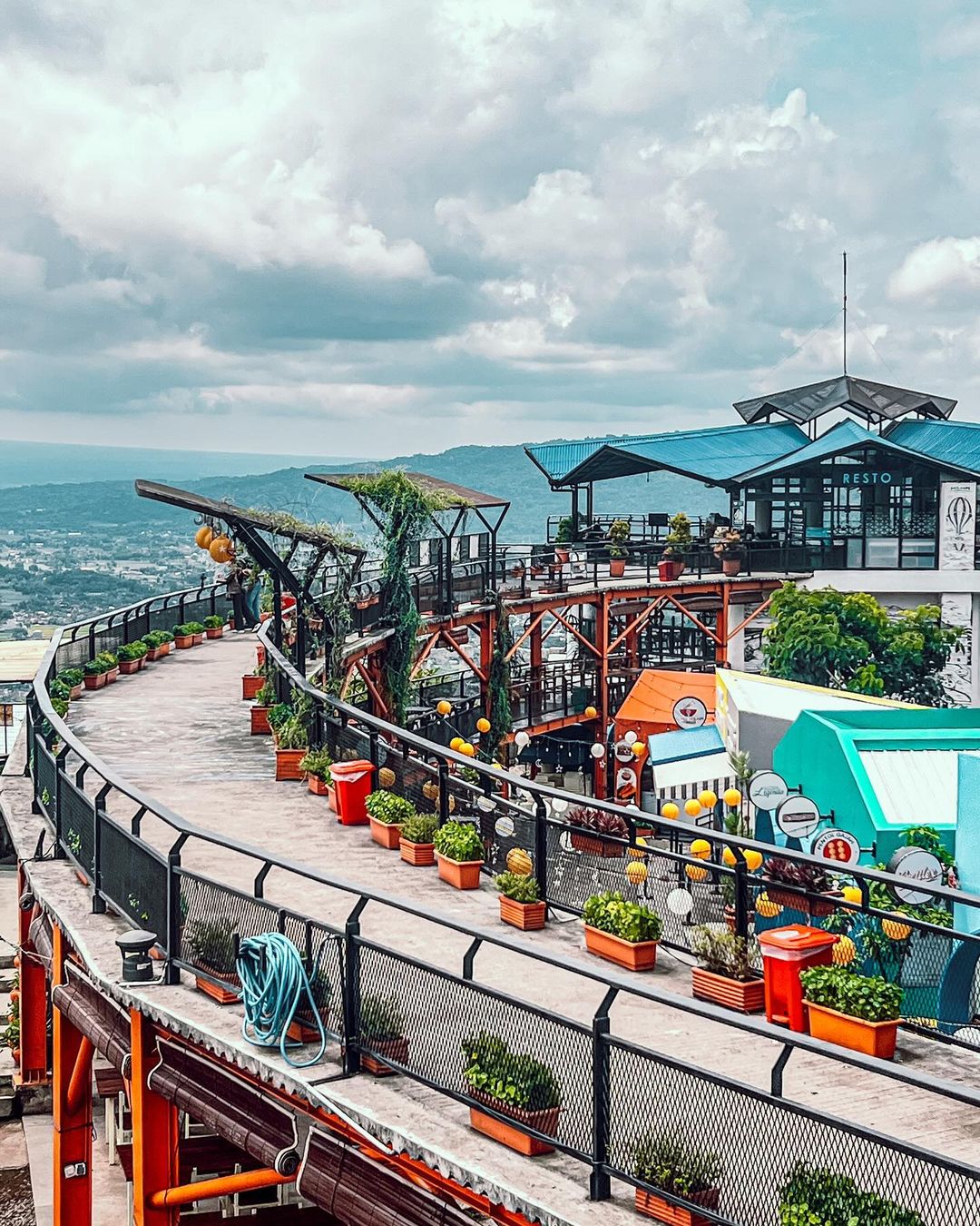 Elevated walkway lined with potted plants leading to multiple levels of HeHa Sky View's restaurant area.