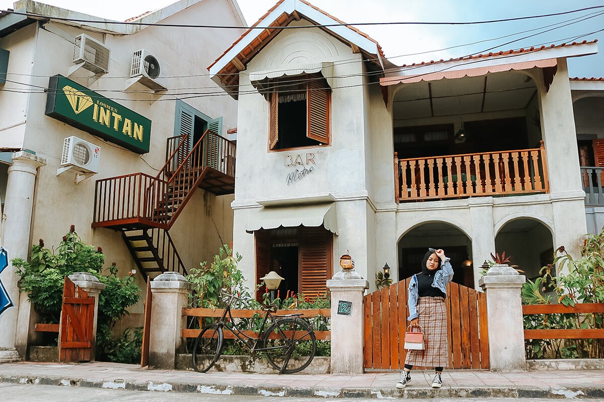 A woman standing in front of an old building named "BAR Metro" at Gamplong Studio Alam.