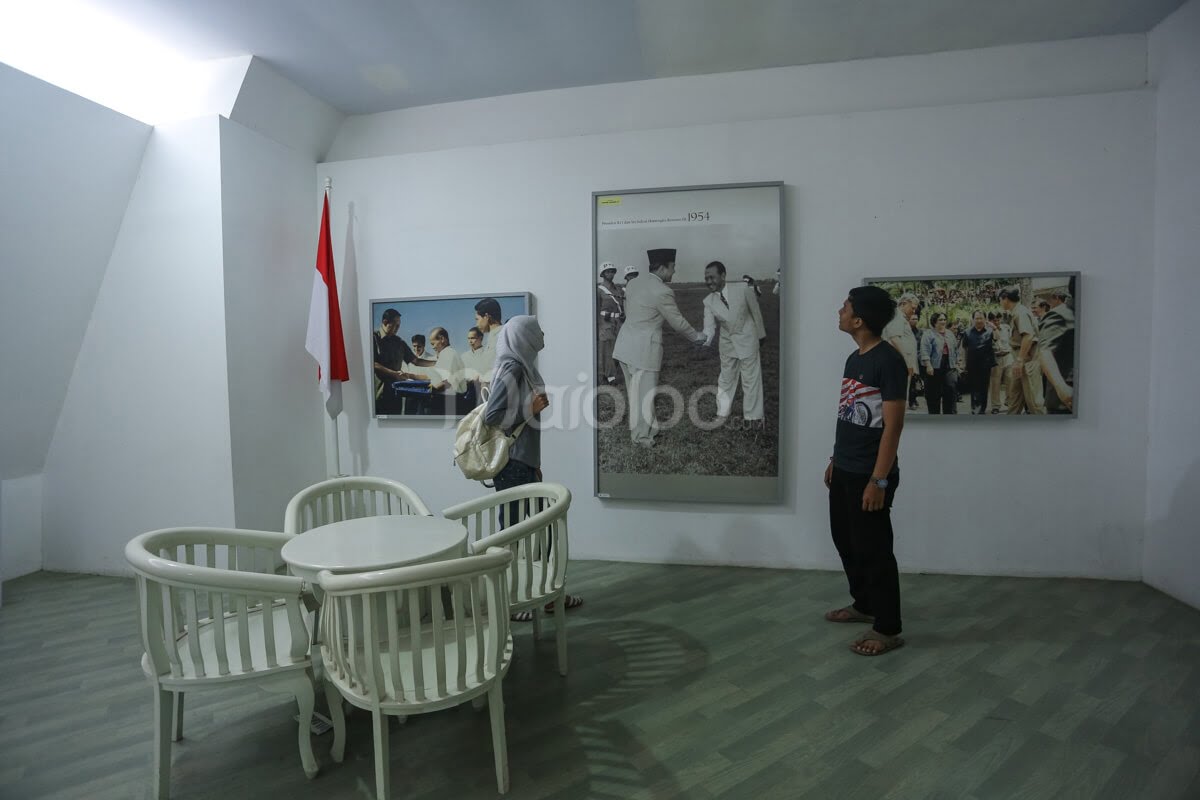 Two visitors in the historical room at Merapi Volcano Museum looking at old photographs.