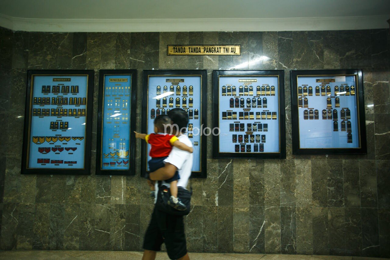 A visitor walking past display boards of Indonesian Air Force rank insignia at the Dirgantara Mandala Museum.