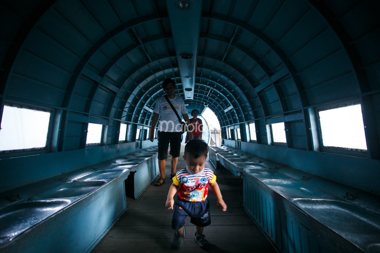 Visitors walking inside the hollow interior of a C-47 Dakota aircraft at the Dirgantara Mandala Museum.