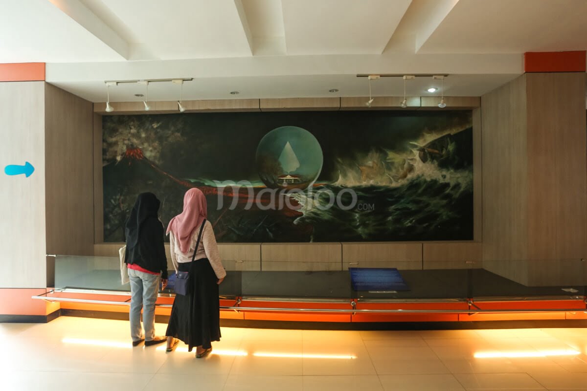 Two visitors looking at an information board about Mount Merapi, Keraton Yogyakarta, and Parangtritis Beach.