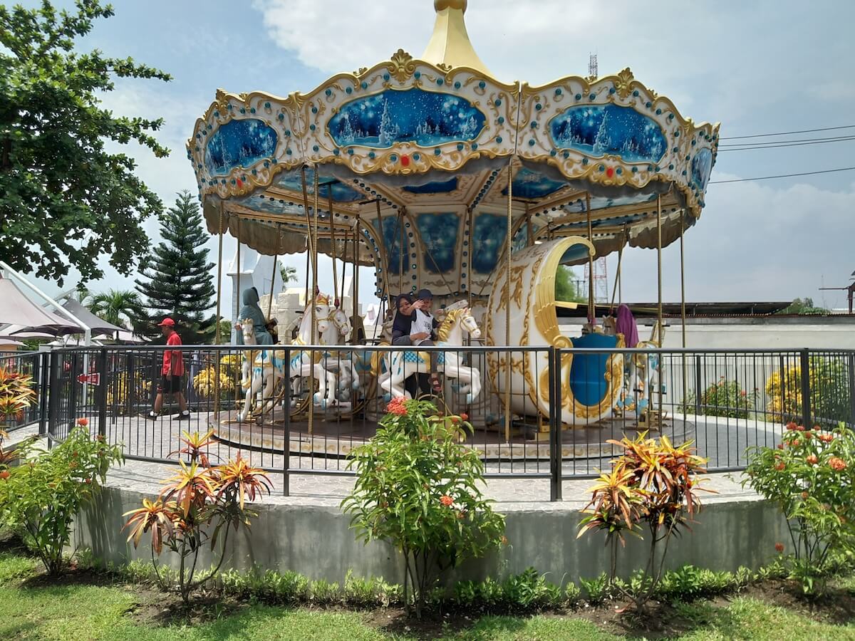 A colorful carousel ride at Kids Fun Park with children and adults enjoying the ride.