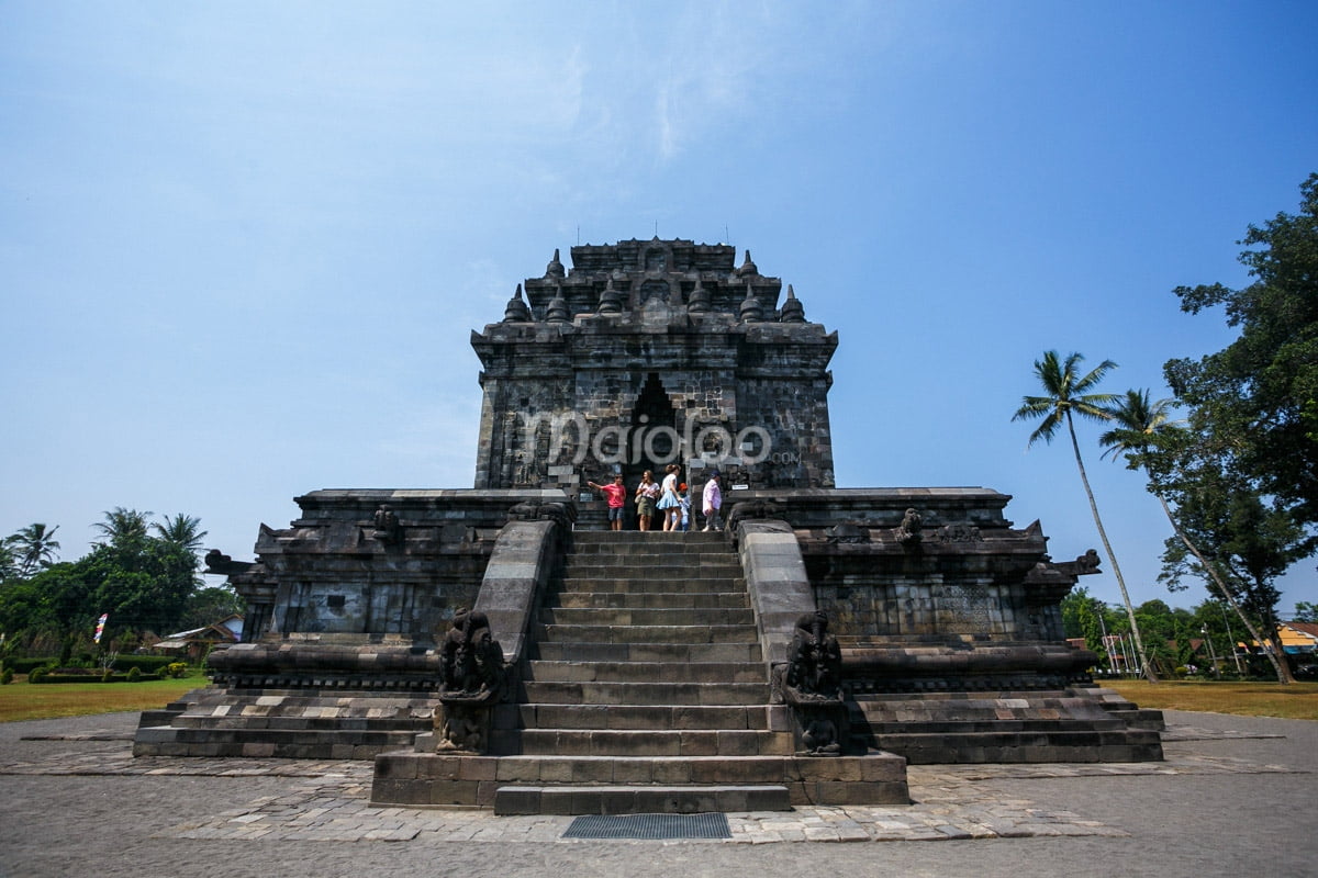 Mendut Temple with tourists on the stairs under a clear blue sky.