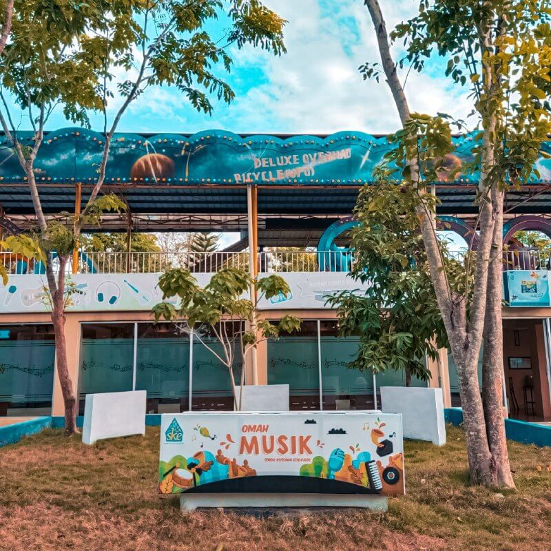 Exterior of Omah Musik at Sindu Kusuma Edupark with trees and a blue sky background.