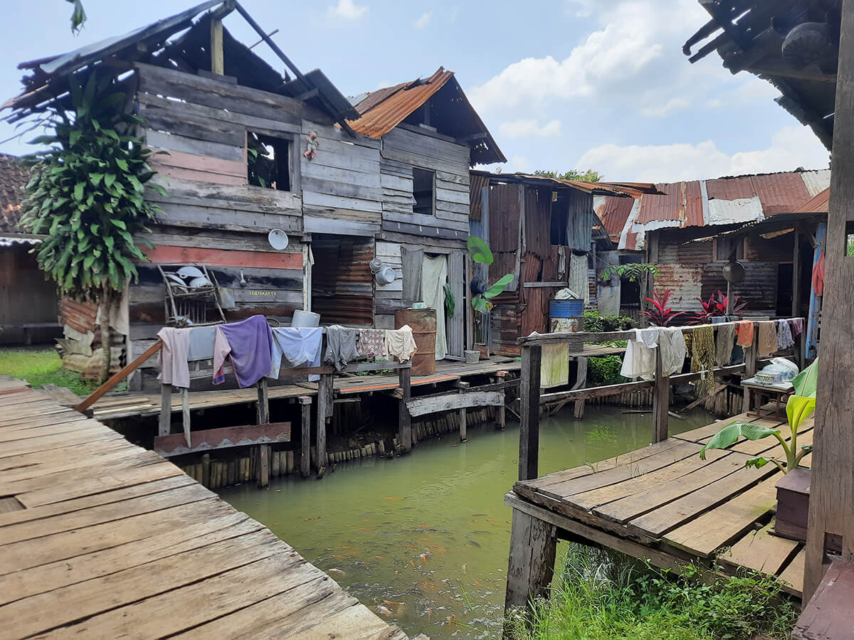 Rustic wooden houses built over a small pond at Gamplong Studio Alam.