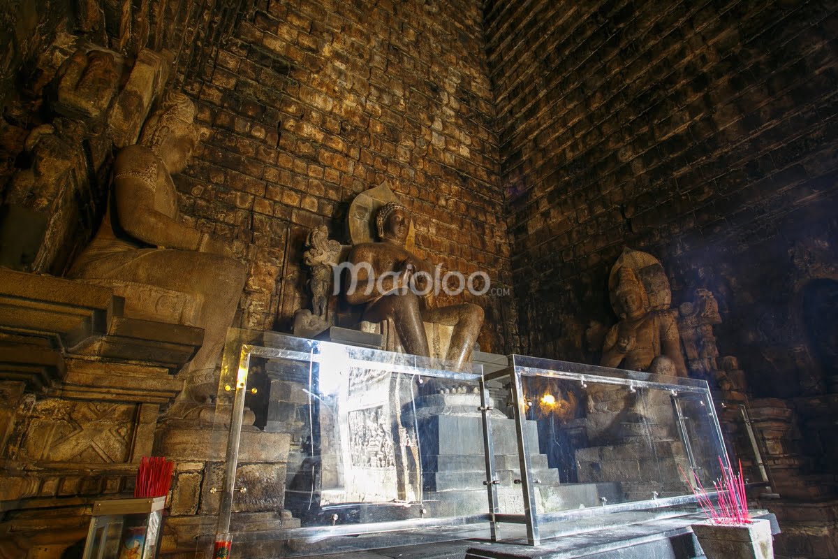 Three Buddha statues inside Mendut Temple, protected by glass.