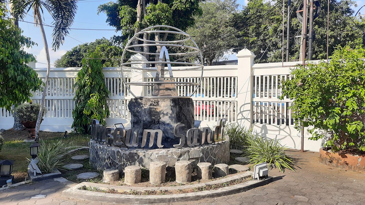 An outdoor sculpture at the Sandi Museum featuring a globe structure and the text "Museum Sandi."