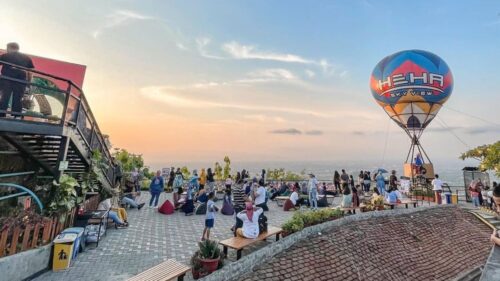 People enjoying the view and activities at HeHa Sky View during sunset, with a hot air balloon in the background.