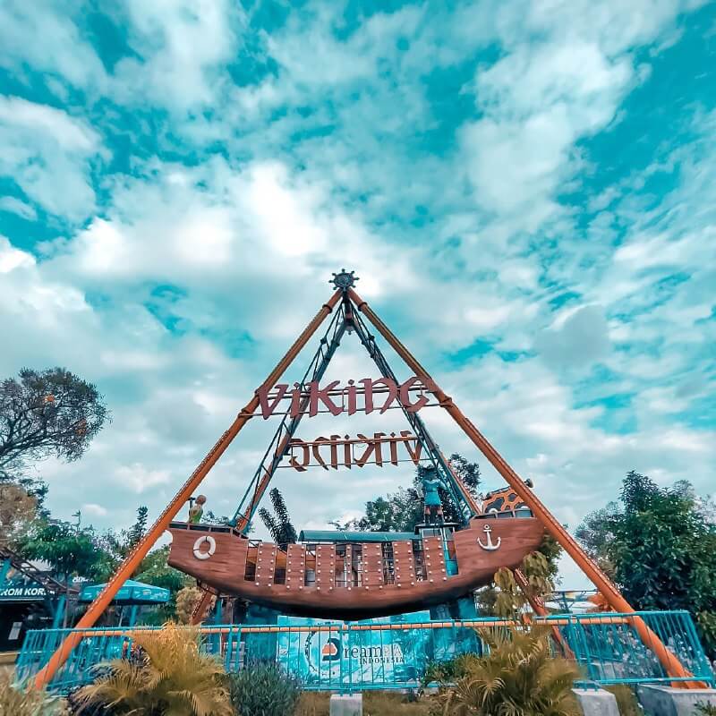 Viking ship ride at Sindu Kusuma Edupark under a partly cloudy sky.