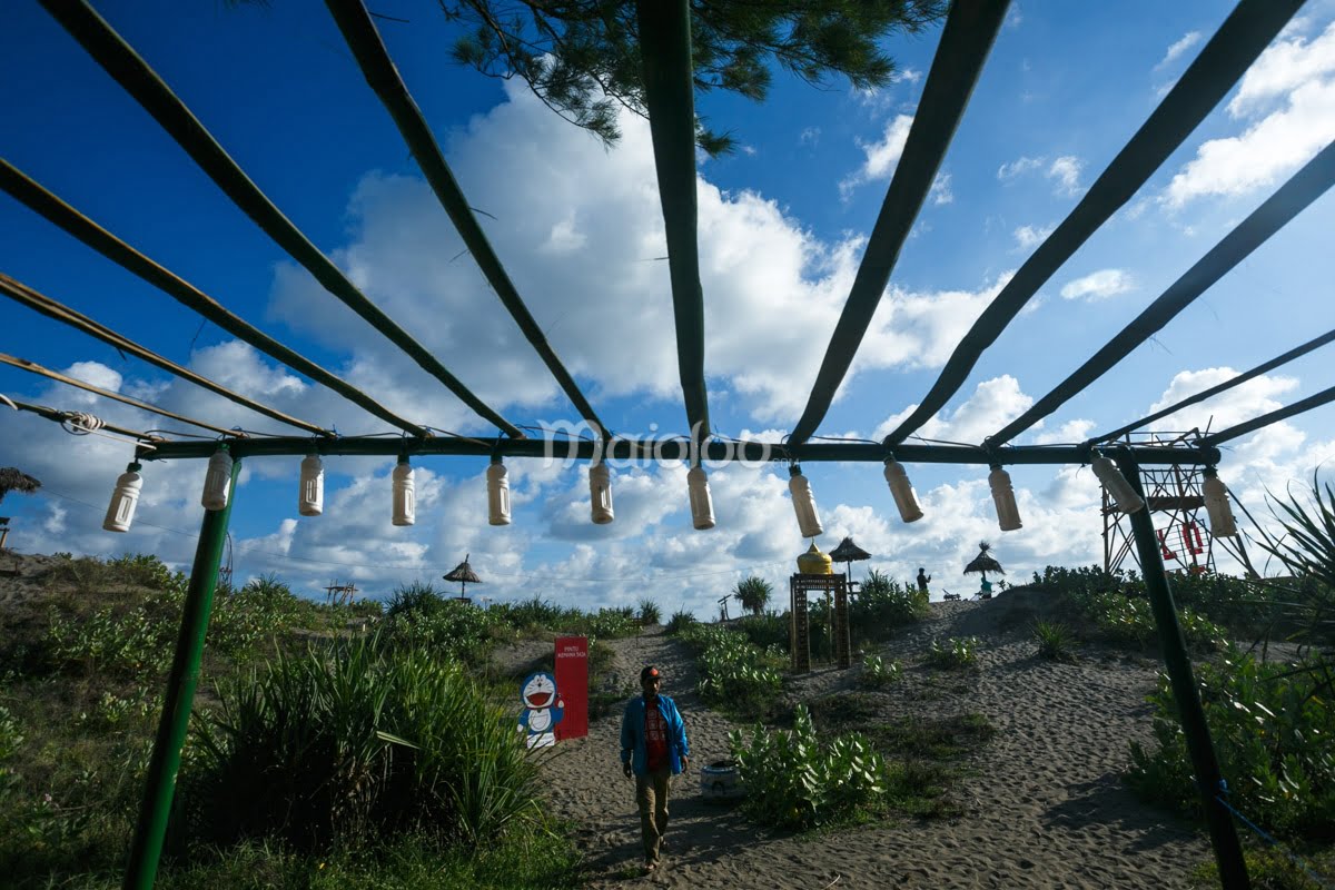 A visitor walking under the bamboo installation with hanging lights at Gardu Action.