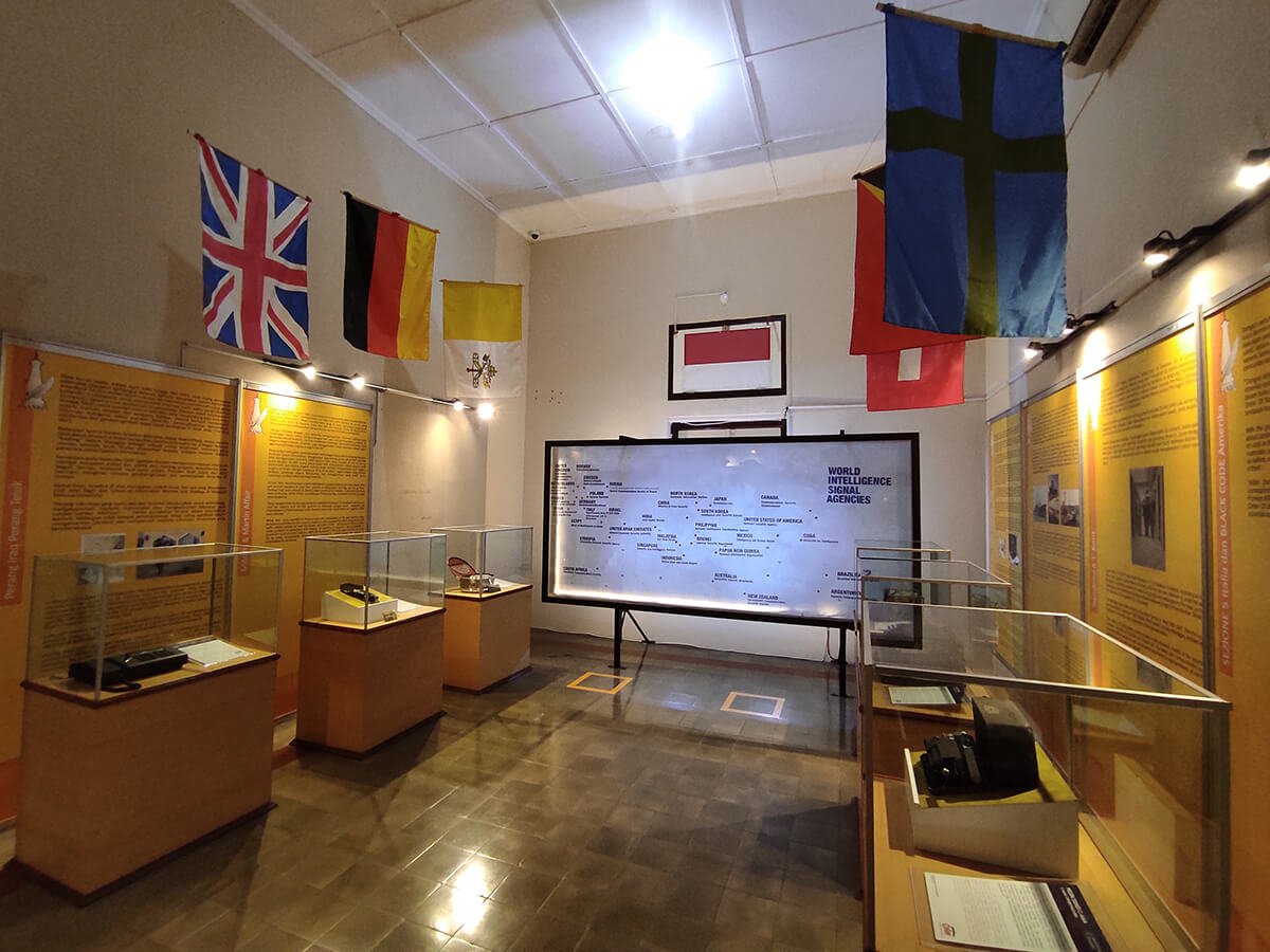 A museum display with flags, information panels, and various communication devices in glass cases, highlighting world intelligence signal agencies.