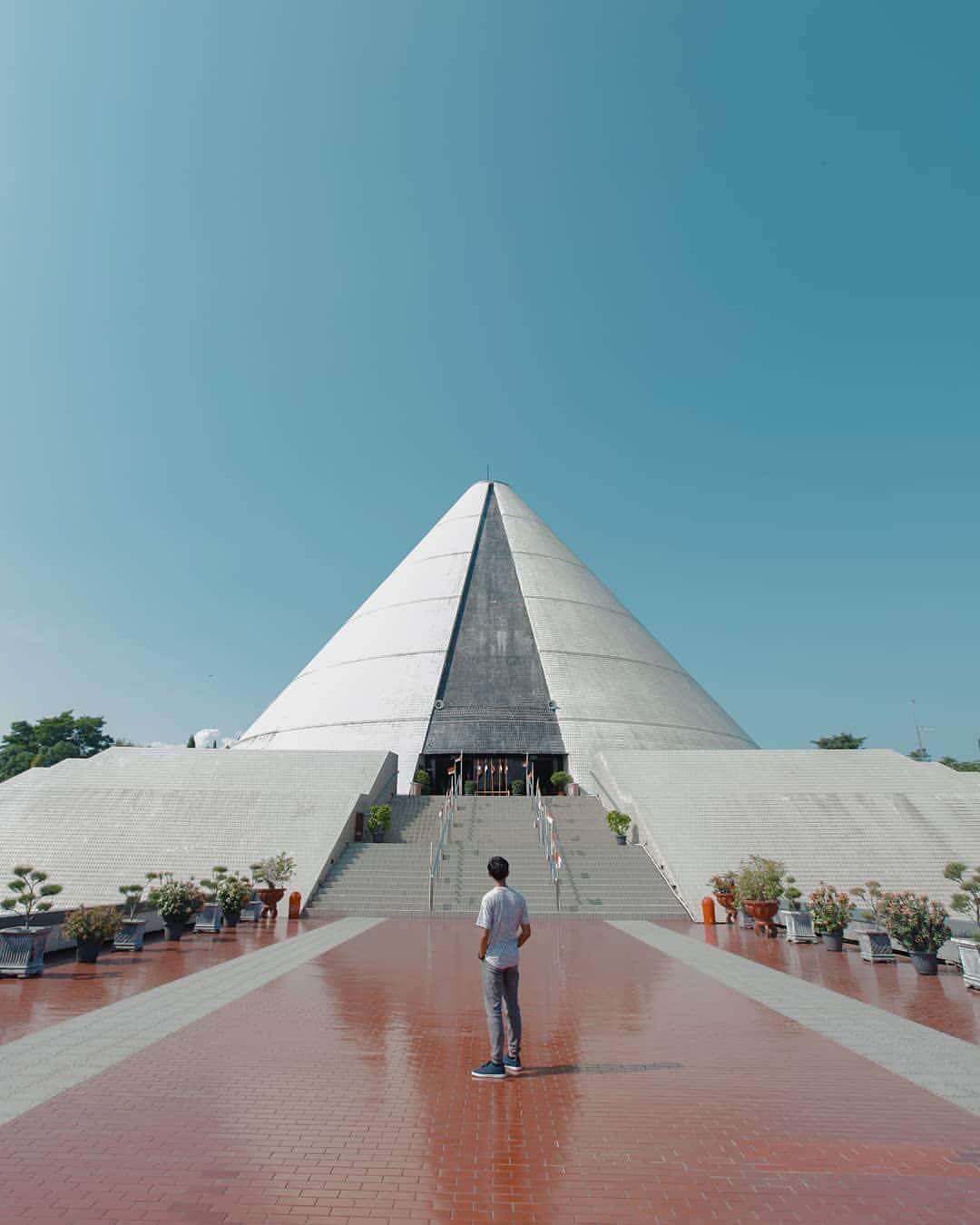 A person standing at the entrance of the cone-shaped Monumen Jogja Kembali in Yogyakarta.