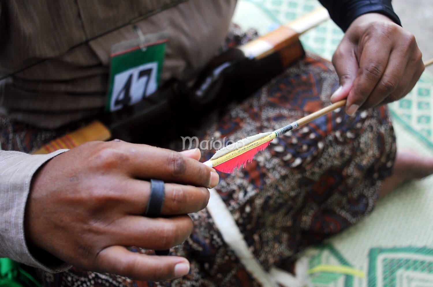 Close-up of a participant examining an arrow during Jemparingan.