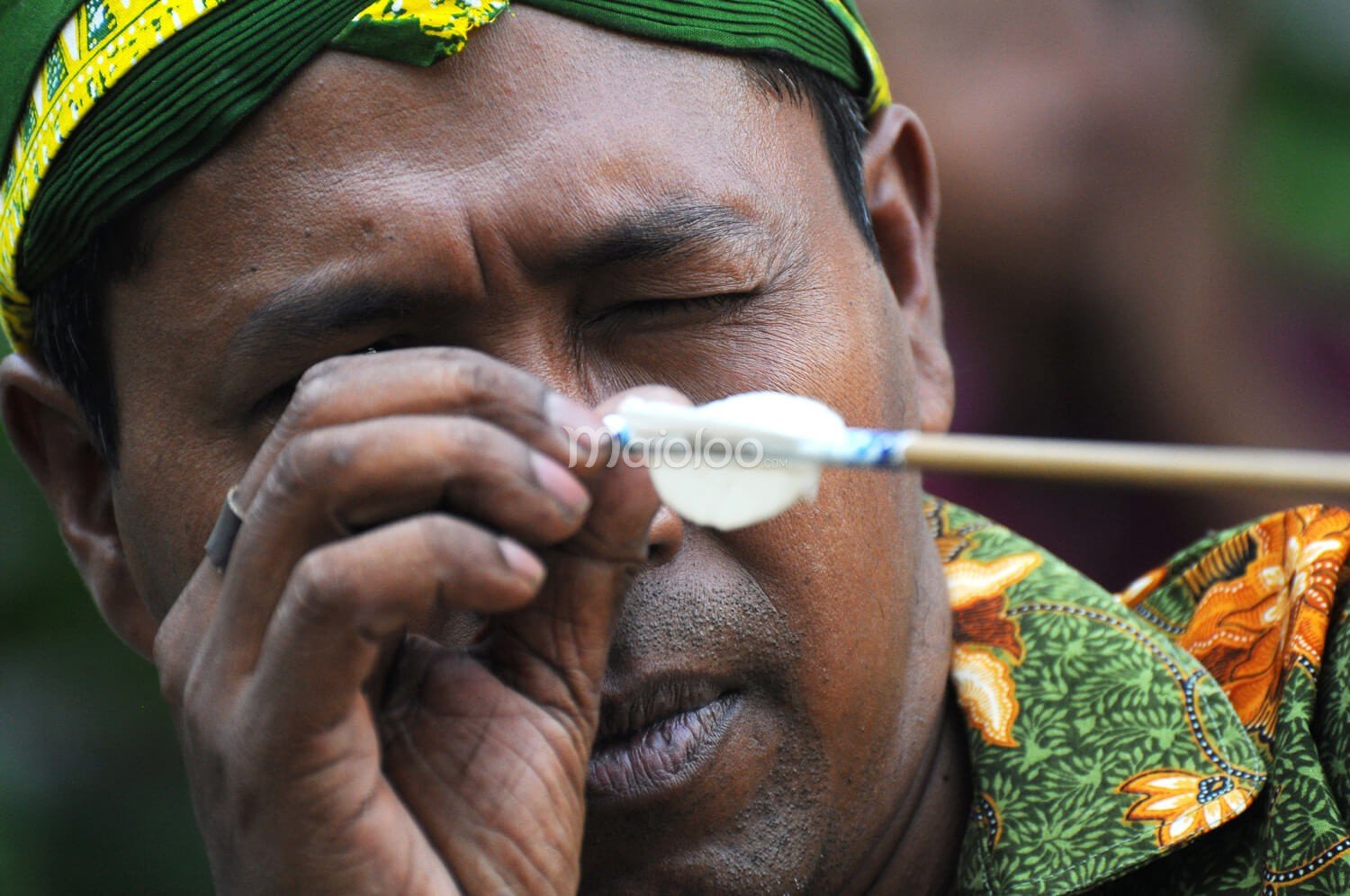 Participant closely examining an arrow during the Jemparingan event.