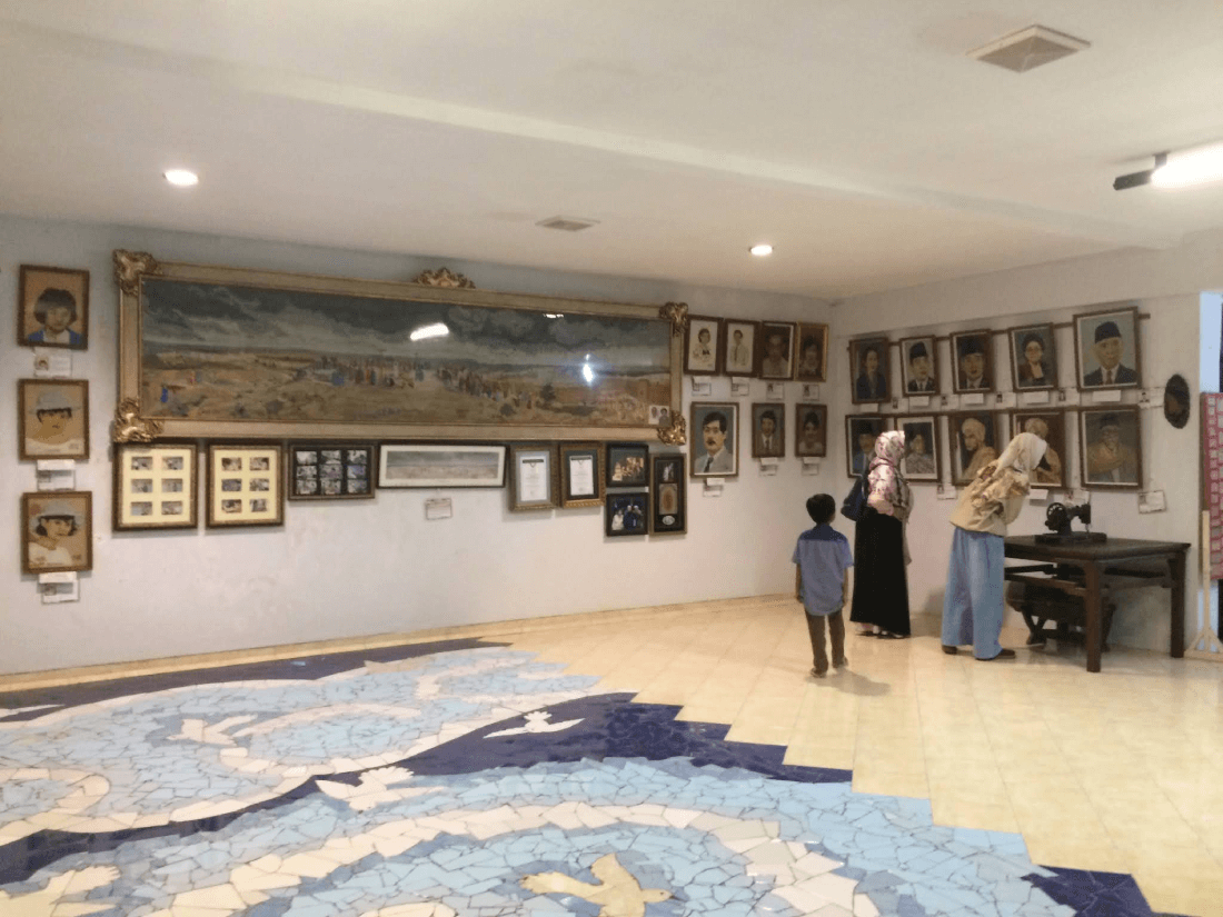 Two women and a child observing portraits and artworks in a gallery at Museum Batik Yogyakarta.