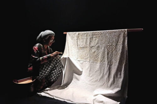 A mannequin creating batik fabric using traditional tools.