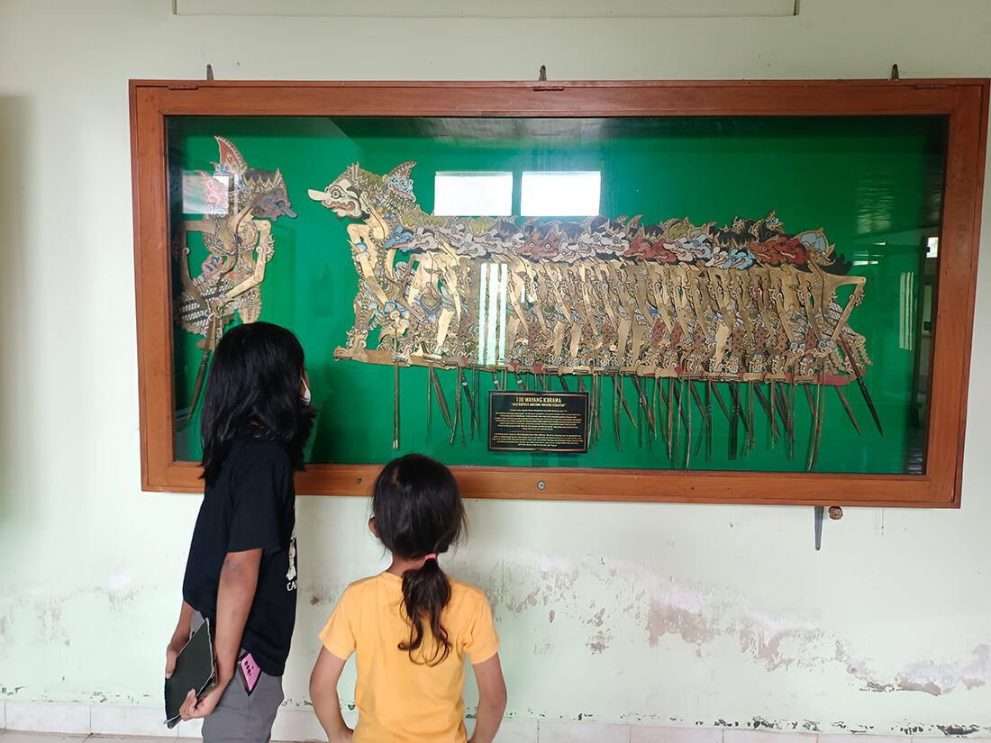 Two children observing a wayang kulit display inside Museum Wayang Kekayon.