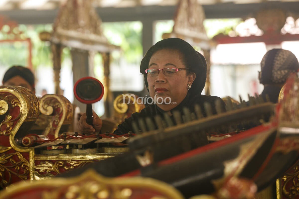 A musician playing a traditional gamelan instrument with focus and precision at Bangsal Sri Manganti in Yogyakarta Palace.