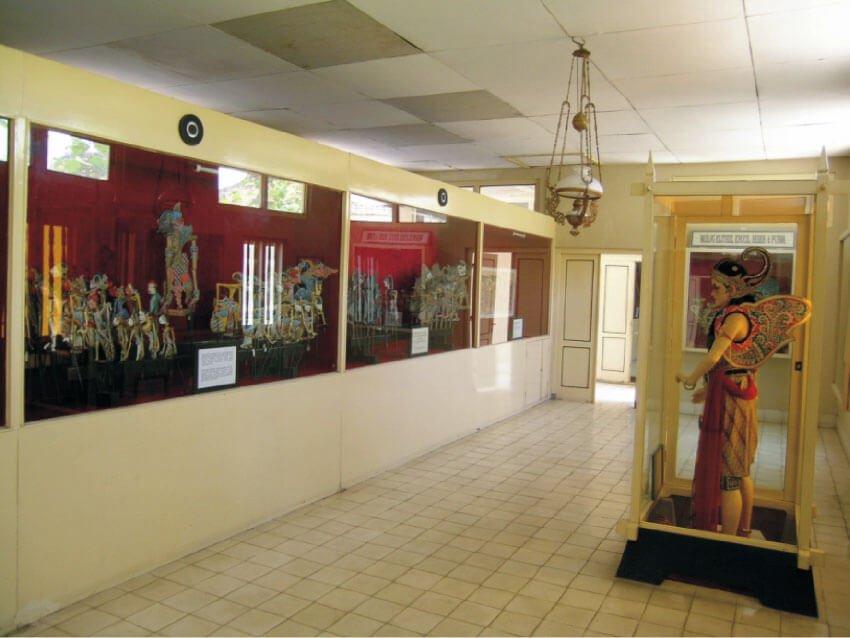 Interior gallery view of Museum Wayang Kekayon displaying various wayang puppets and a statue.