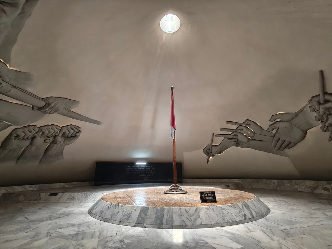 Interior of the Garbha Graha room with a flag and relief sculptures at Monumen Jogja Kembali.