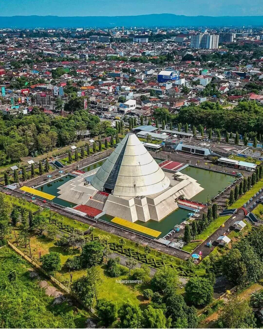 Aerial view of Monumen Jogja Kembali surrounded by a cityscape and lush greenery in Yogyakarta.