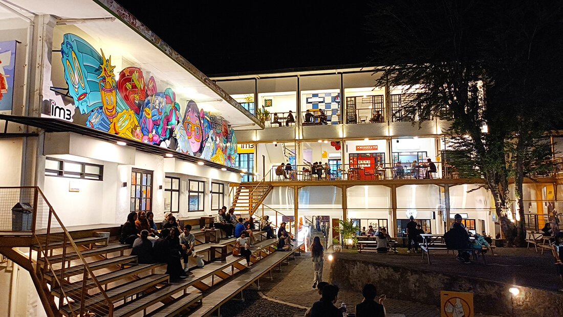 People gather in a lively courtyard outside JNM Bloc at night.