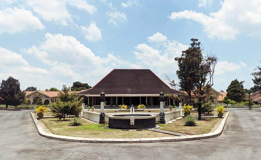 A traditional building with a fountain in front at Pura Pakualaman Museum, Yogyakarta, on a sunny day.