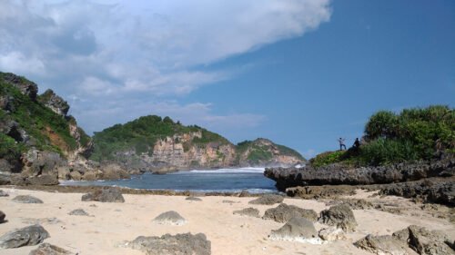 A beautiful beach with rocky cliffs and sandy shore under a clear blue sky.