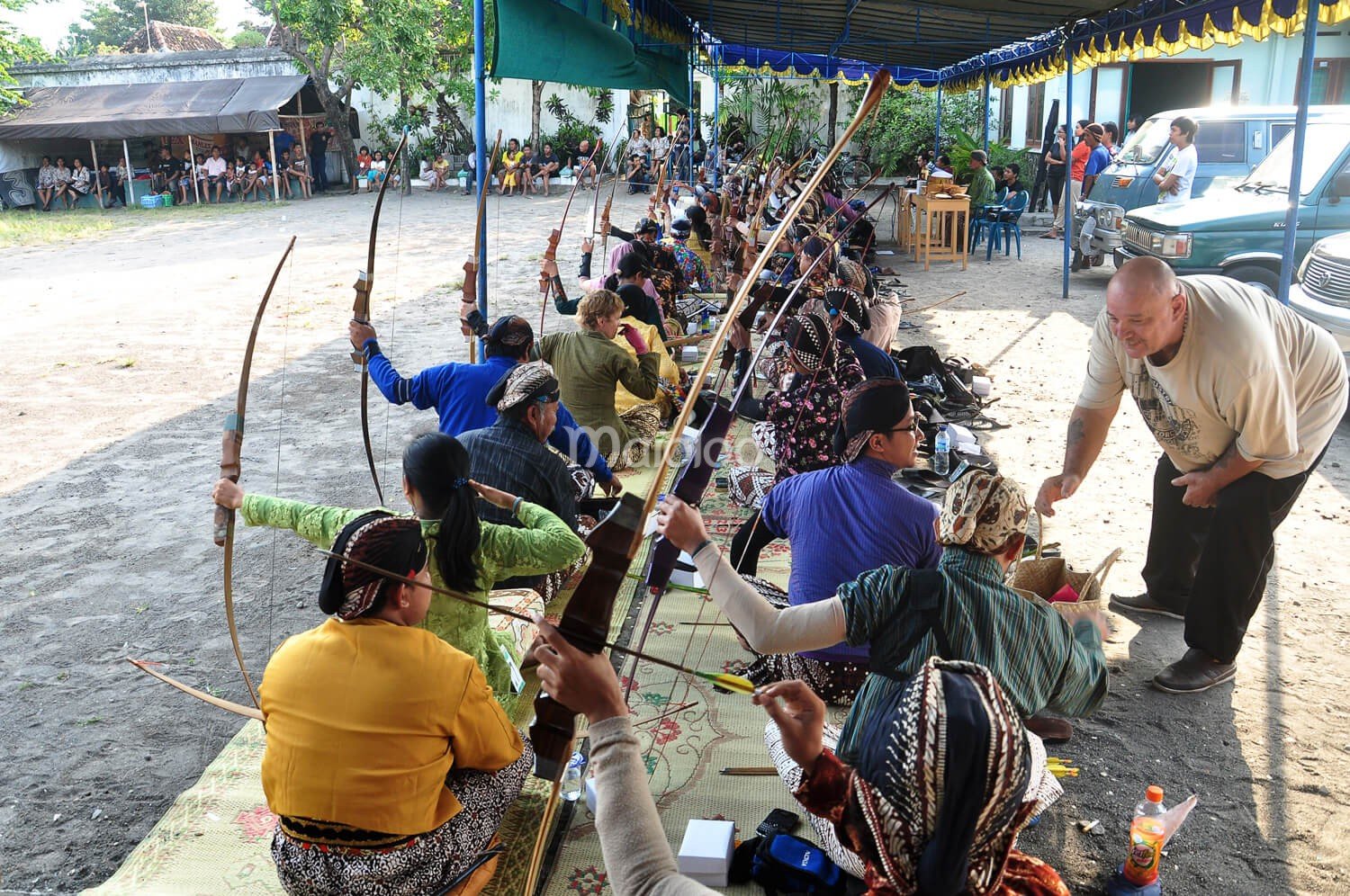 Archers sitting cross-legged, preparing to shoot in a traditional Jemparingan event.