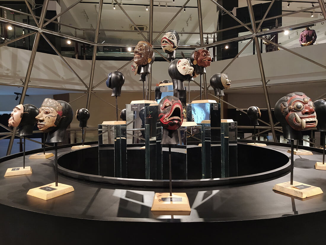 Display of traditional Javanese masks arranged on stands at the Sonobudoyo Museum.