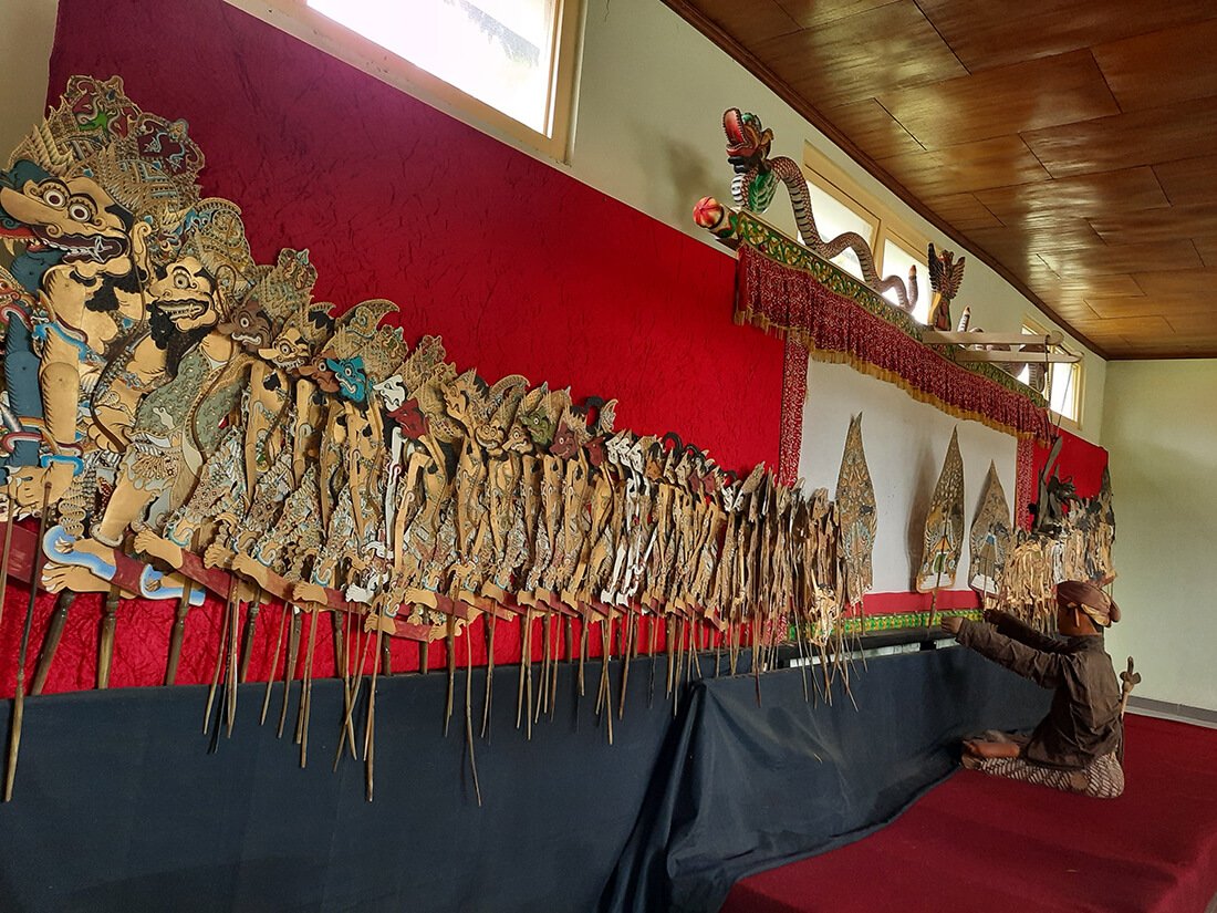 A traditional Javanese puppet stage setup with wayang kulit puppets and a puppet master figure at Museum Wayang Kekayon.