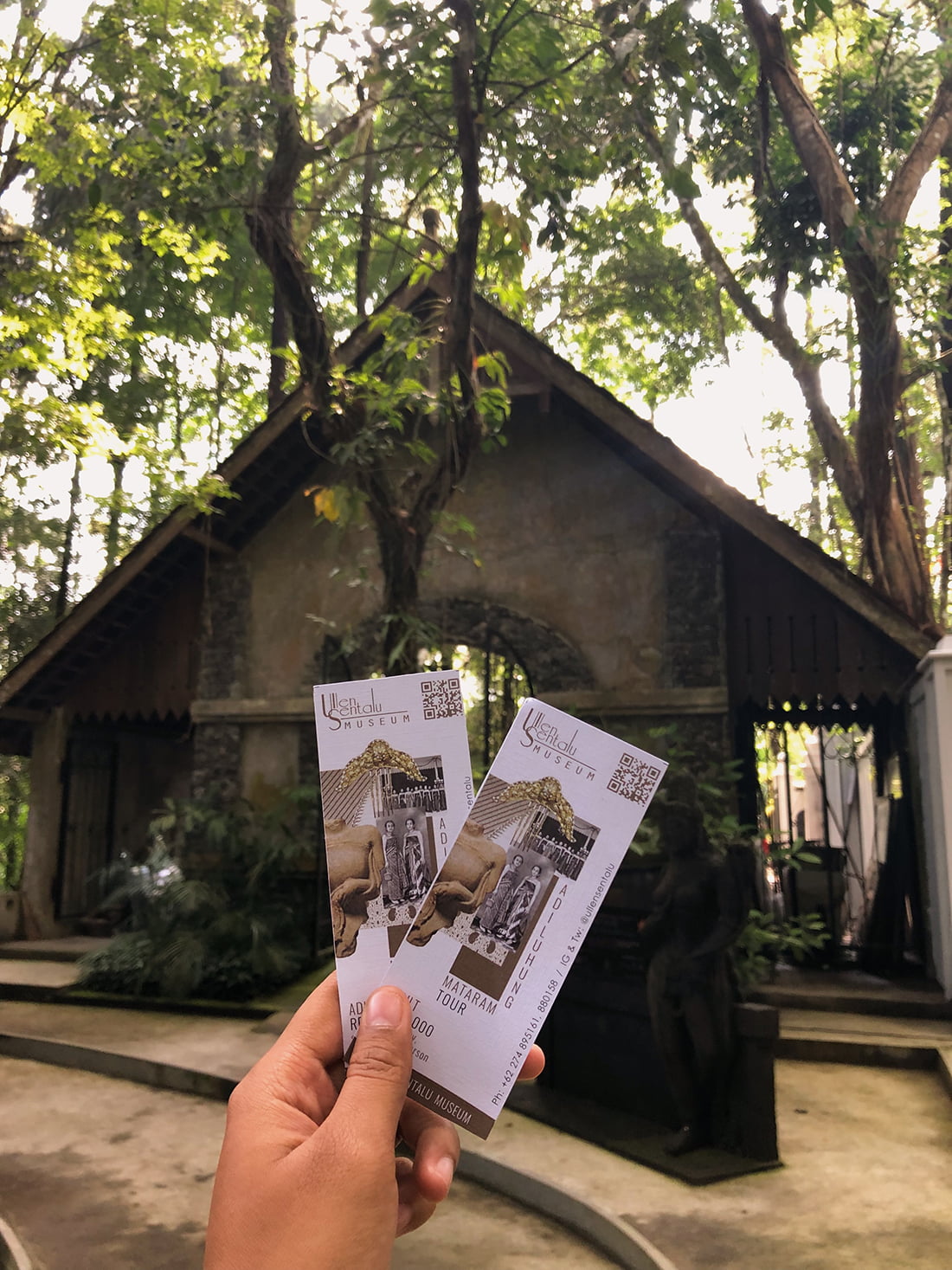 Hand holding two entrance tickets to Ullen Sentalu Museum.