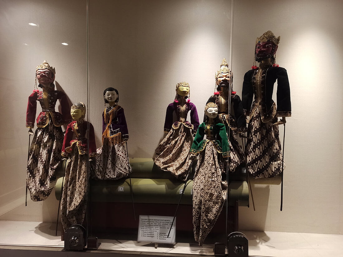 Traditional Javanese wooden puppets (wayang golek) displayed in a glass case at the Sonobudoyo Museum.