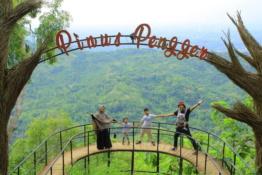 Family posing on a curved platform with a "Pinus Pengger" sign and green hills in the background.