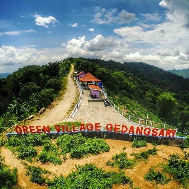 An entrance view of Green Village Gedangsari with large signage and lush green hills in Gunungkidul, Yogyakarta.