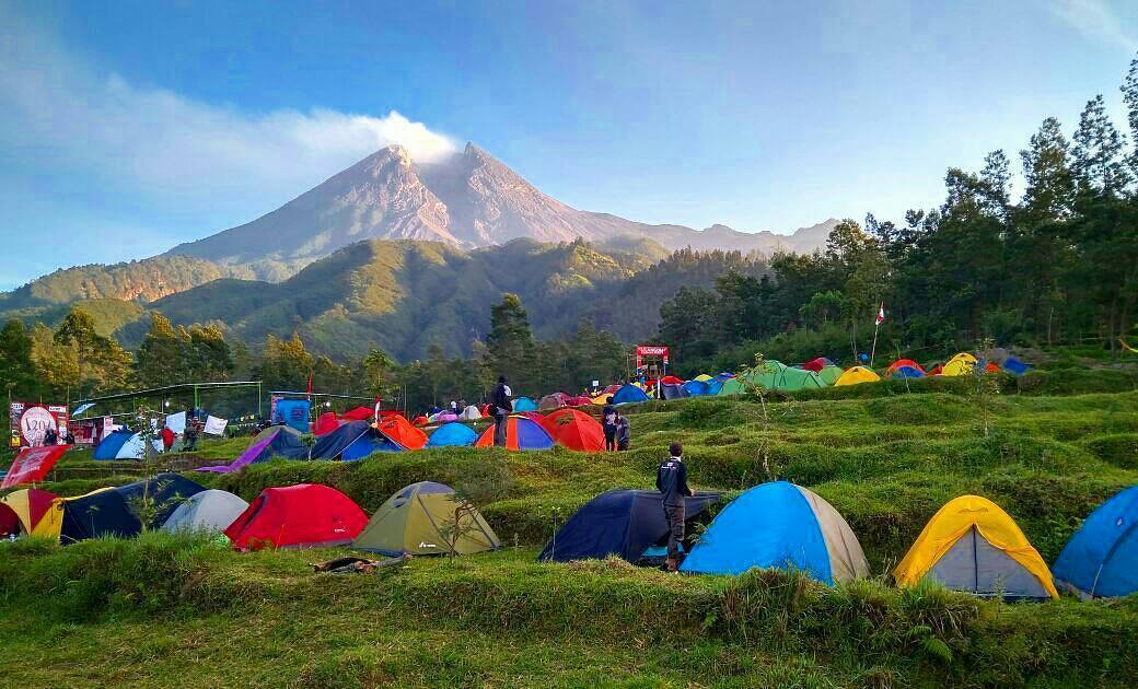 Colorful tents set up at Klangon Hill with Mount Merapi in the background on a clear day.