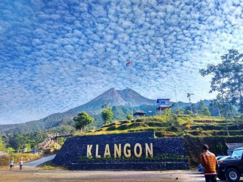 Klangon Hill with Mount Merapi in the background under a blue sky with scattered clouds.