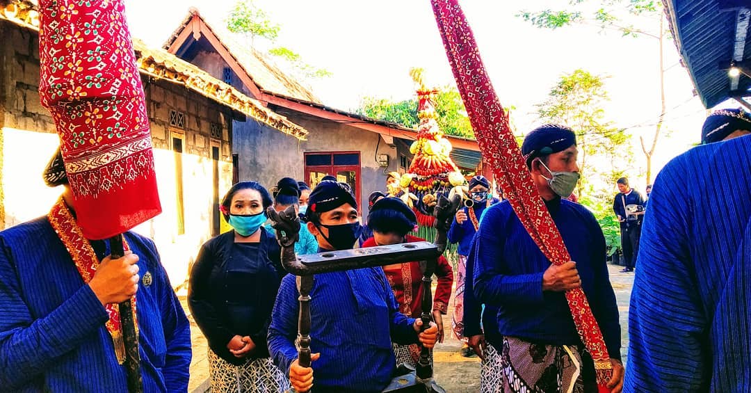 Traditional Javanese procession during the Islamic New Year at Suroloyo Peak, featuring people dressed in blue attire and carrying ceremonial heirlooms.