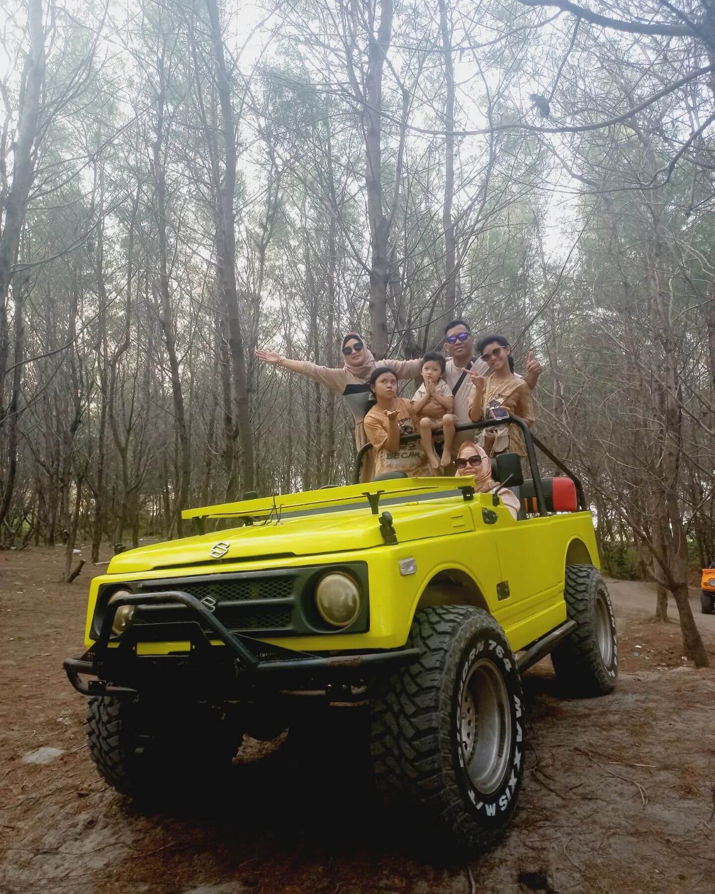 Family enjoying an off-road adventure in a yellow jeep at Hutan Pinus Pengger.