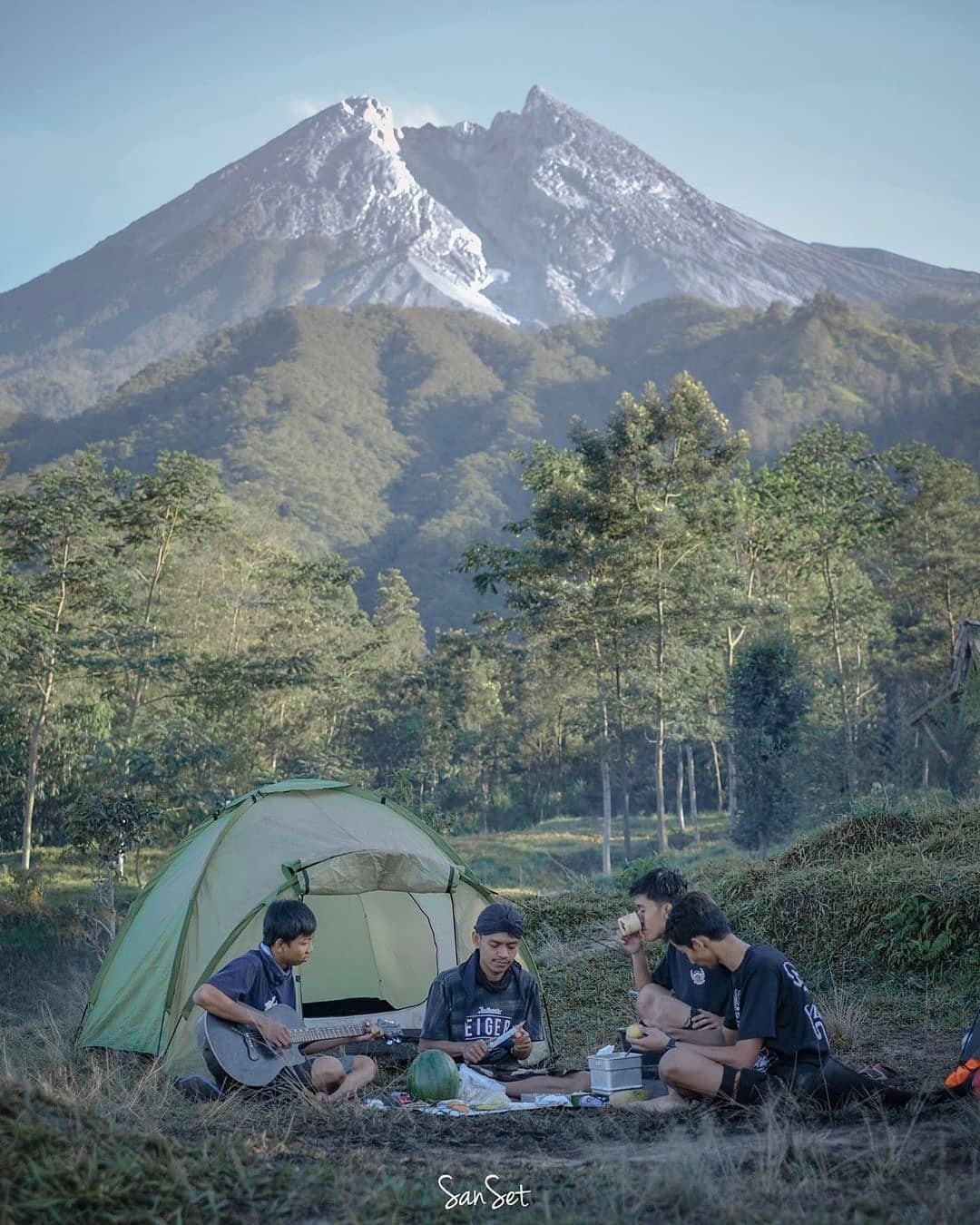 Campers enjoying breakfast in front of a tent at Klangon Hill with Mount Merapi in the background.