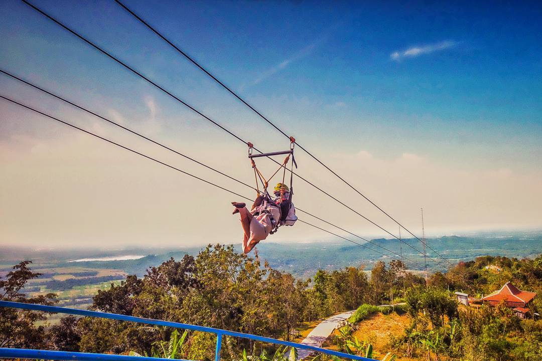 Person enjoying a thrilling ride on the flying fox at Green Village Gedangsari in Gunungkidul, Yogyakarta.