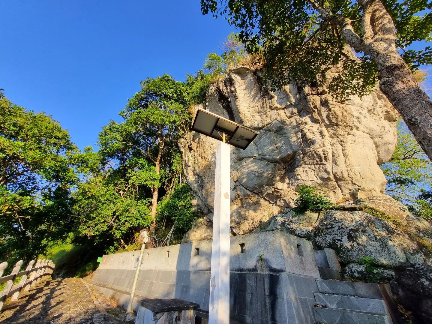 A designated location for the Sadranan ceremony at Gambar Mountain, featuring a prominent rock formation and surrounding trees.