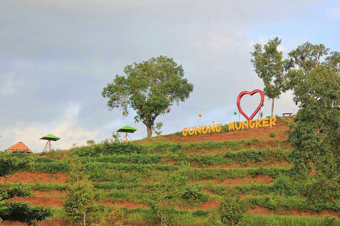 View of Mount Mungker with a heart-shaped structure and the "GUNUNG MUNGKER" sign on a hill.