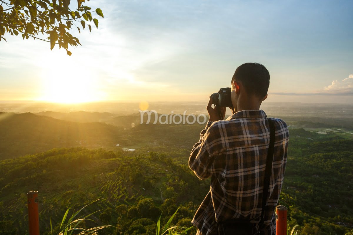 A photographer taking a picture of the stunning sunset over the landscape from Becici Peak.