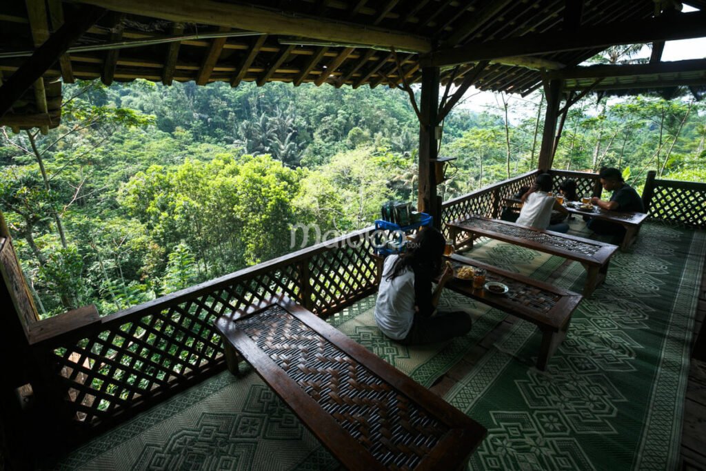 Visitors dining at a cozy café with a view of lush greenery at Nglinggo Tea Plantation, Kulon Progo, Jogja.