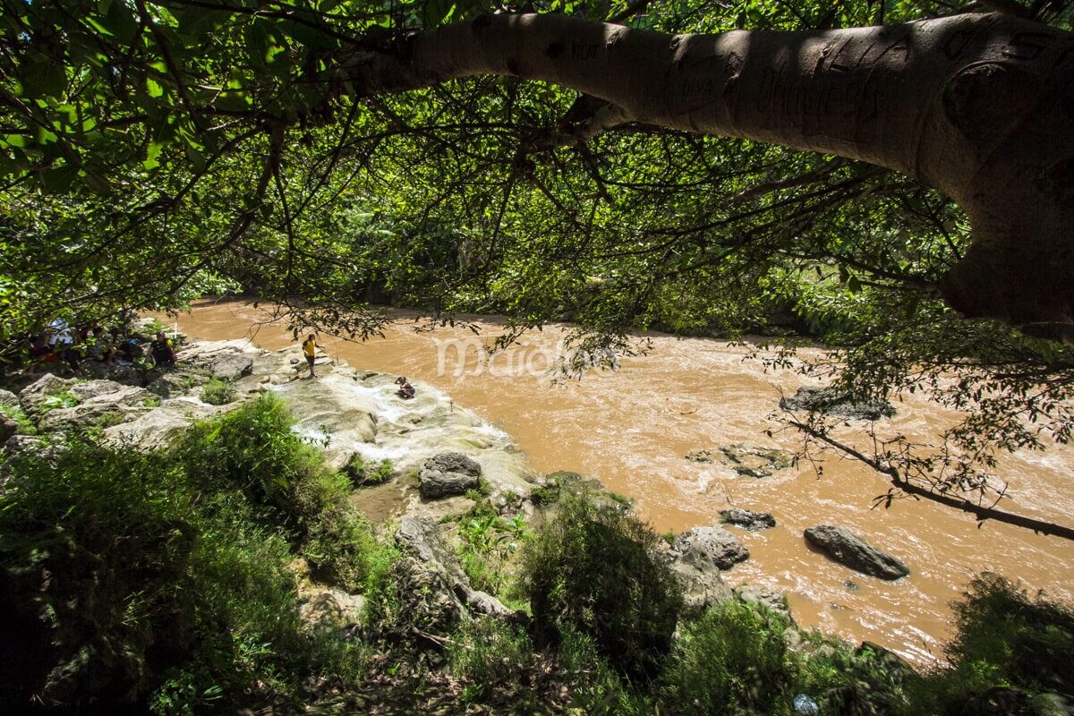 View of visitors enjoying the serene environment by the Oyo River near Sri Gethuk Waterfall in Yogyakarta, Indonesia.