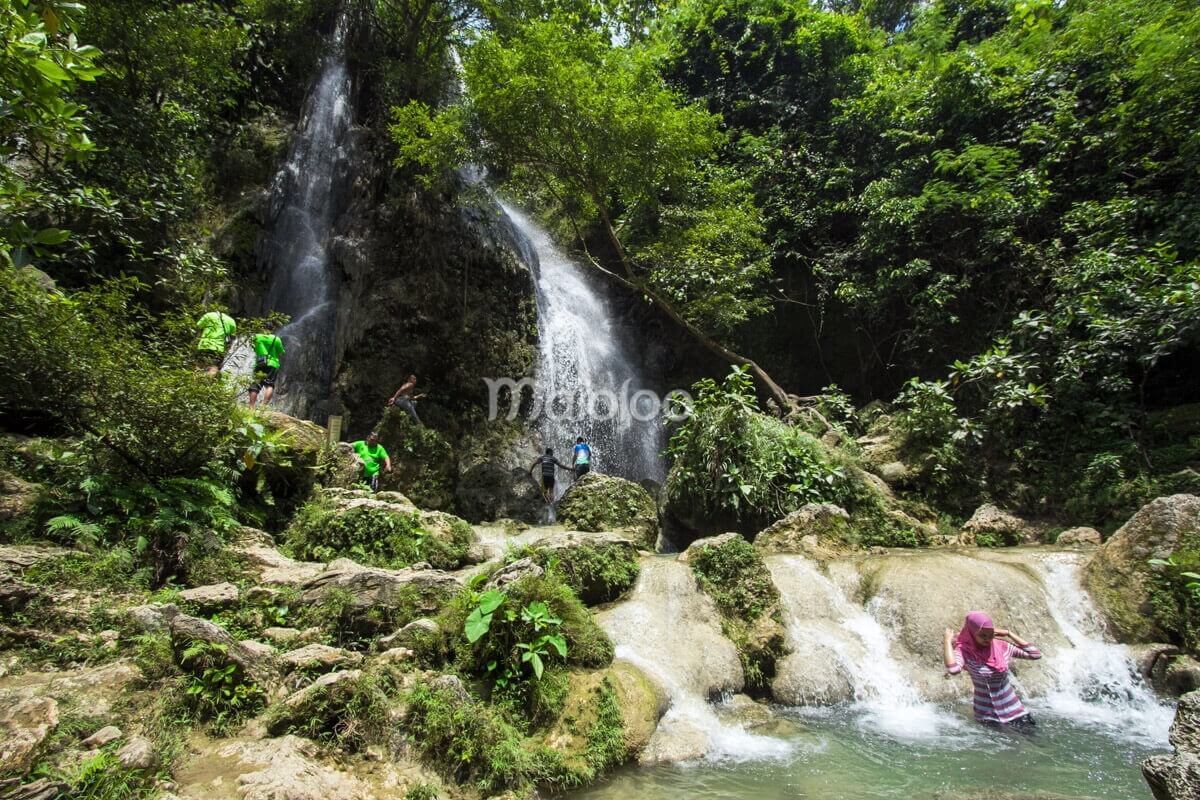 People enjoying the water and surroundings at Sri Gethuk Waterfall in Yogyakarta, Indonesia.