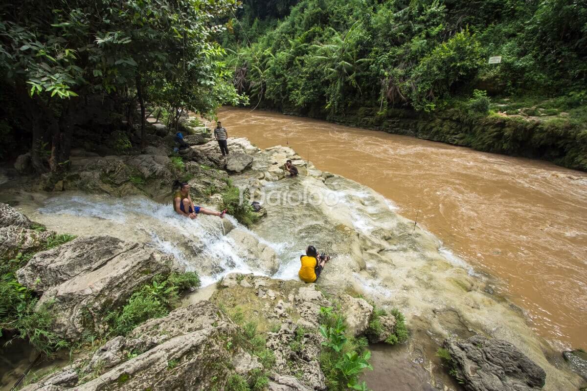 People relaxing by the Oyo River near Sri Gethuk Waterfall in Yogyakarta, Indonesia.